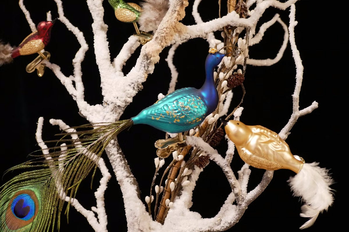 Decoratieve kerstornamenten met vogelmotieven op besneeuwde takken.