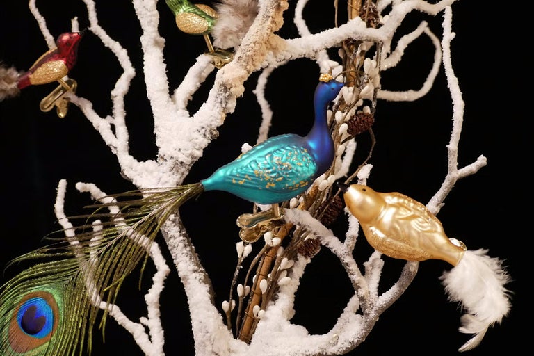 Decoratieve kerstornamenten met vogelmotieven op besneeuwde takken.