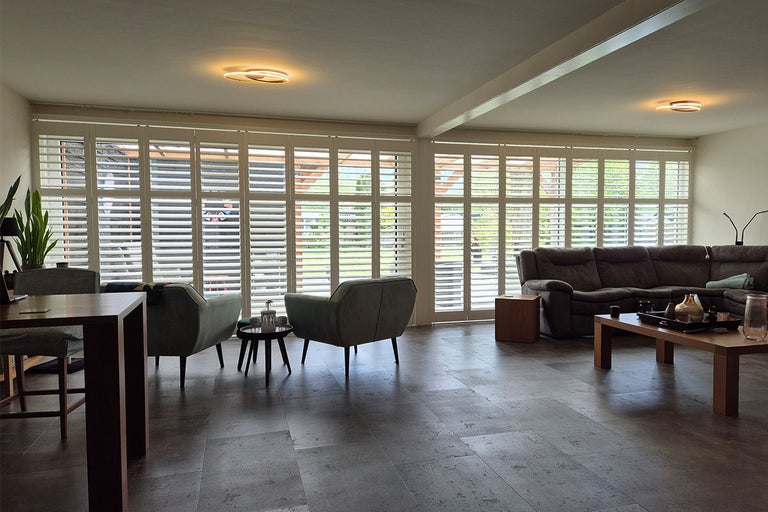 Lichte woonkamer met luiken, bank en fauteuils