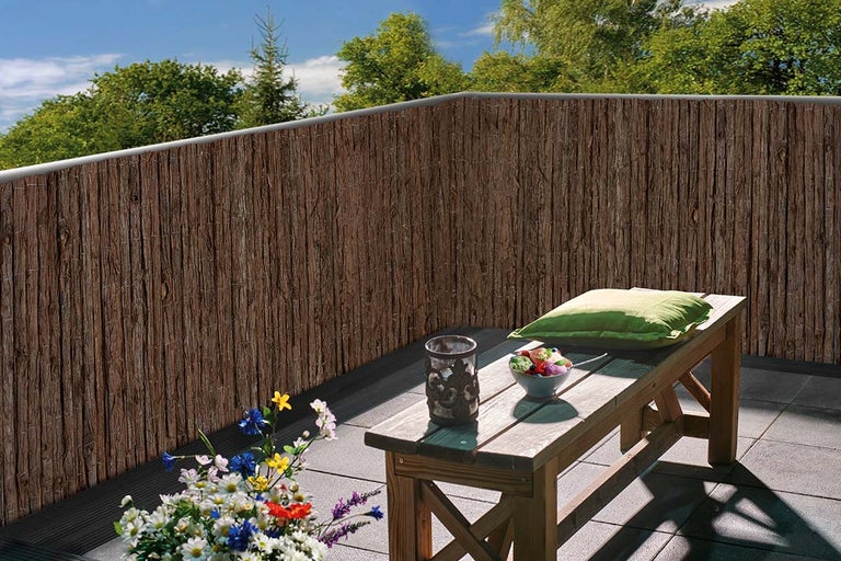 Balkon met privacyscherm van natuurlijke materialen, houten bank en decoratie