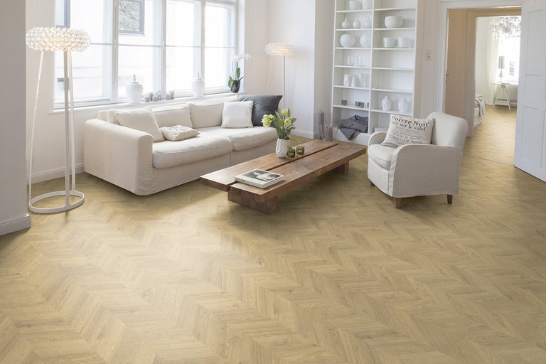 Lichte woonkamer met bank, fauteuil, houten tafel en visgraatparket