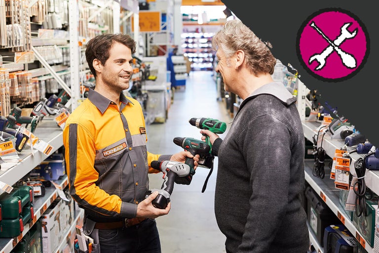 Een Hornbach medewerker adviseert een klant bij de selectie van boormachines in de winkel.