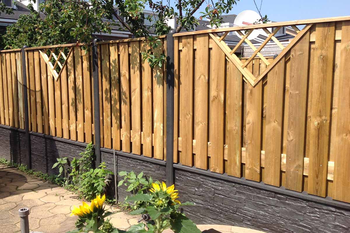 Houten schutting met betonnen voet en decoratieve elementen