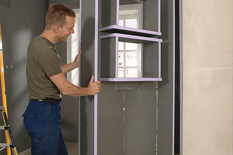 Ambachtsman monteert bouwplaten binnenshuis voor wanddecoratie met schapelementen.