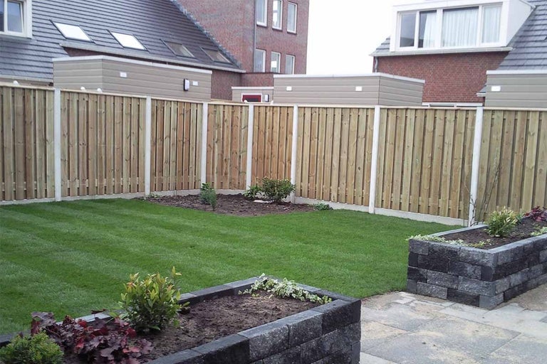 Een tuin met een houten schutting en een gazon.