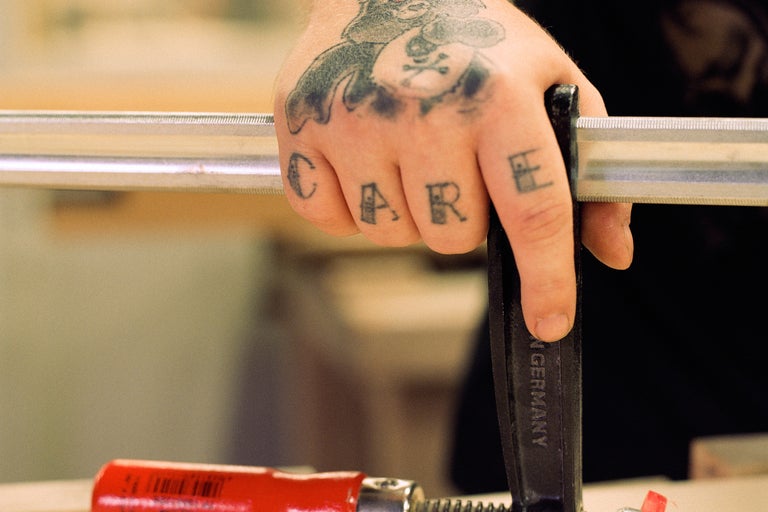 Hand met tatoeages houdt een lijmklem vast