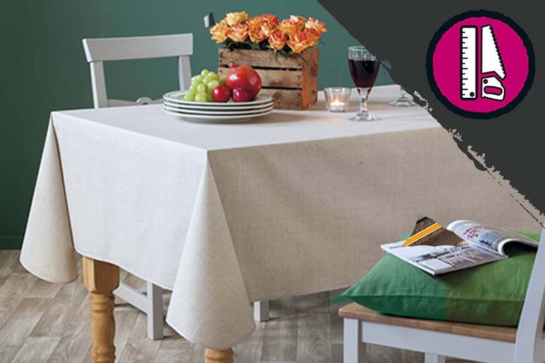 Gedekte tafel met tafelkleed, servies, bloemen, drank en decoratie.