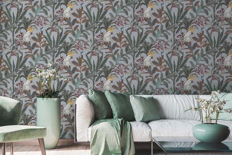 Woonkamer met een patroonbehang met plantmotieven en kaketoes achter een witte bank.