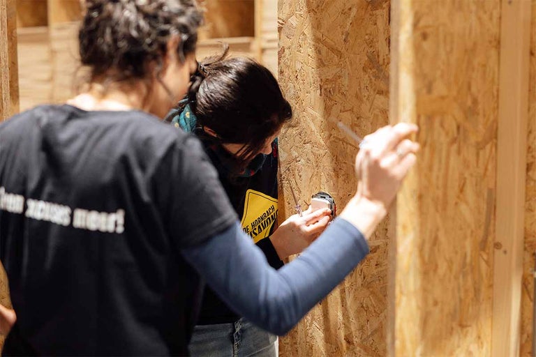 Twee mensen installeren een stopcontact op een houten wand met een schroevendraaier