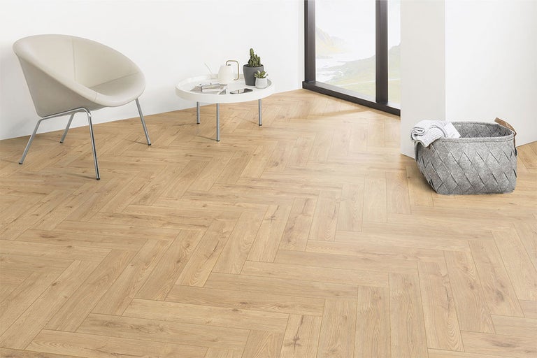 Lichte kamer met visgraatparket, stoel, tafel en mand