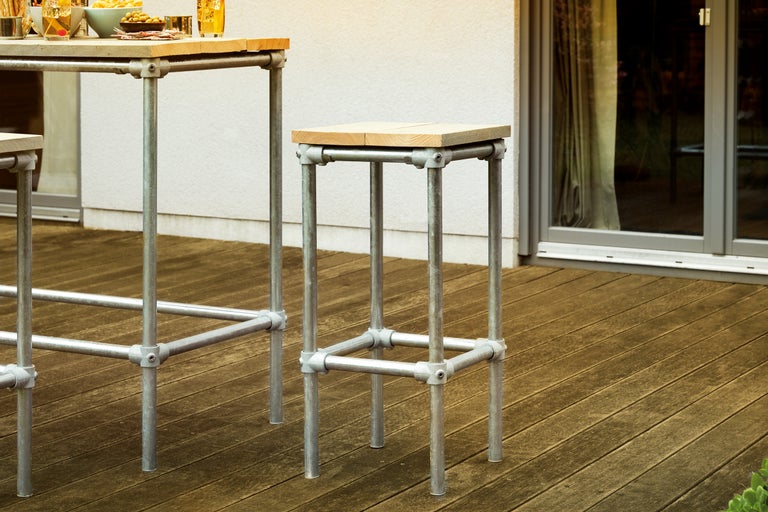 Barkruk en statafel met houten bladen en metalen frame op een terras