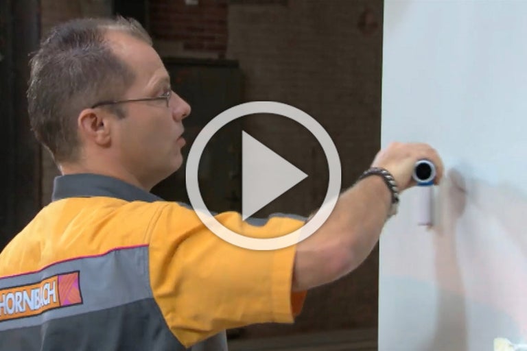 Een persoon met een verfroller schildert een muur. Afspeelsymbool