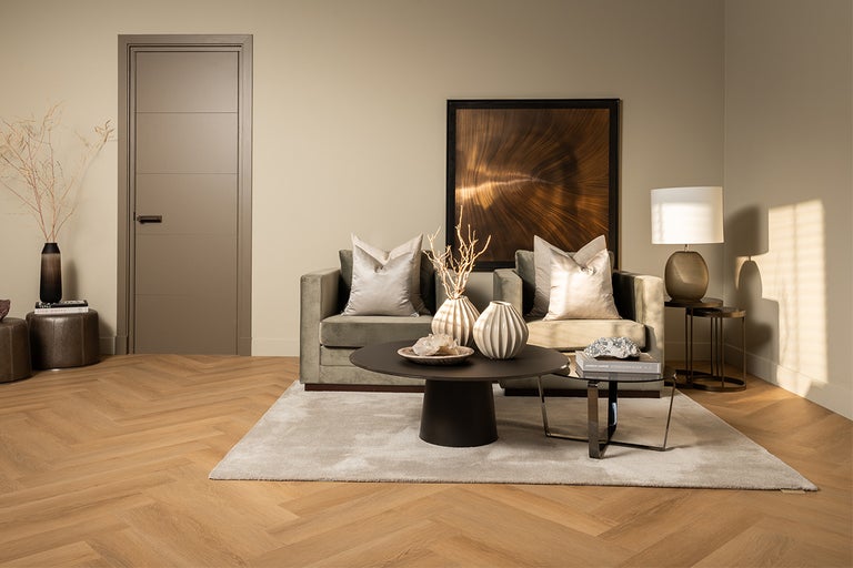 Woonkamer met deur, bank, tafel en decoratie op houten vloer