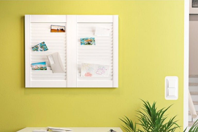 Wandrek met jaloezie-look voor het opbergen van brieven en notities aan een gele muur