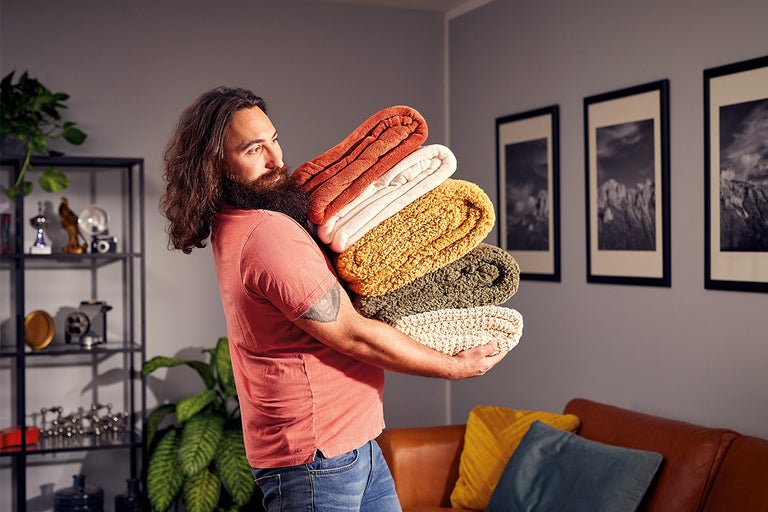Man draagt een stapel opgevouwen dekens in de woonkamer
