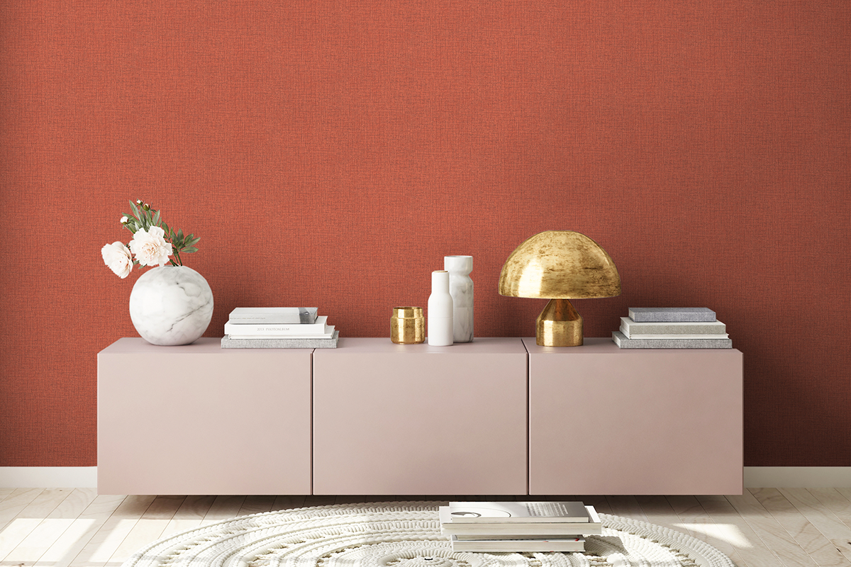 Moderne woonkamer met terracotta structuurbehang, een licht dressoir met decoratie, gouden lamp en rond tapijt op een houten vloer.