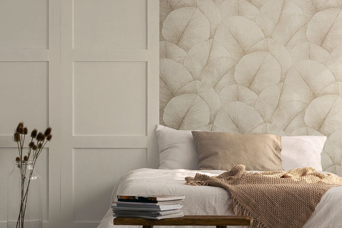 Slaapkamer met bladerbehang, bed en decoratie voor een gezellige sfeer.