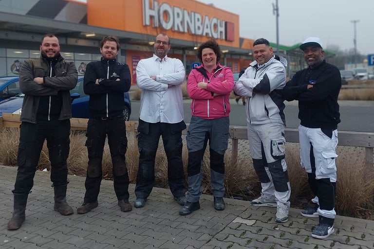 Een groep vakmensen staat voor een Hornbach bouwmarkt.