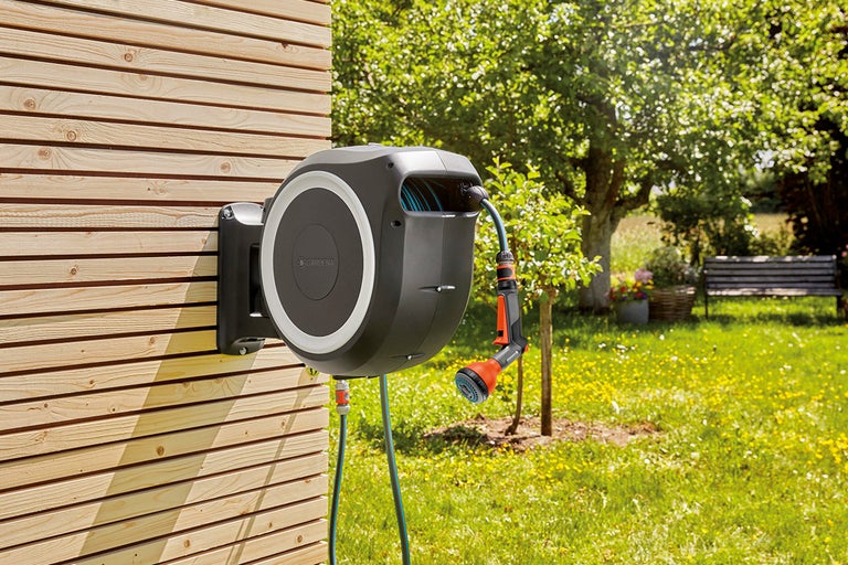 Tuinslangbox met tuinslang en spuitmond aan een houten wand