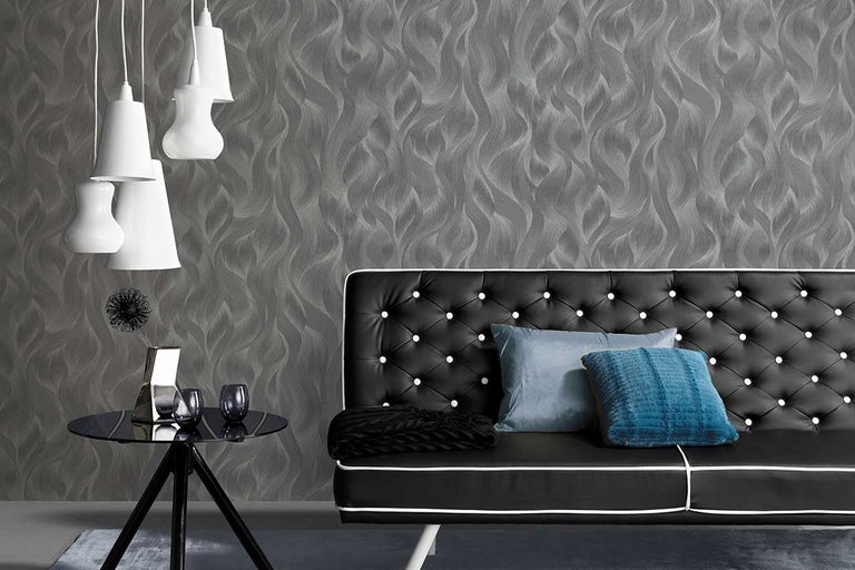 Woonkamer met grijs patroonbehang, zwarte bank met knopen, kussens en lampen