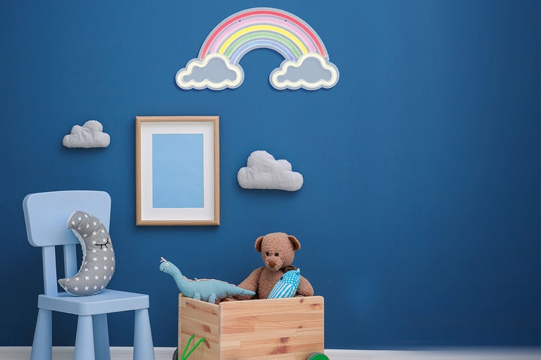 Kinderkamer met houten speelgoed, stoel, fotolijst en wanddecoratie in de vorm van wolken en een regenboog.