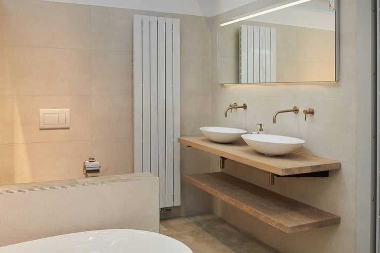 Lichte badkamer met dubbele wastafel op houten tafelblad en verlichte spiegel