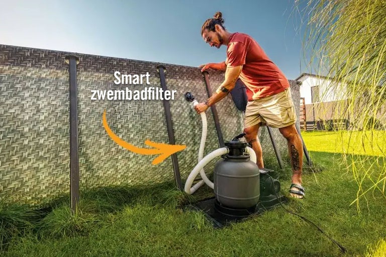 Een man sluit een zandfilter aan op een zwembad