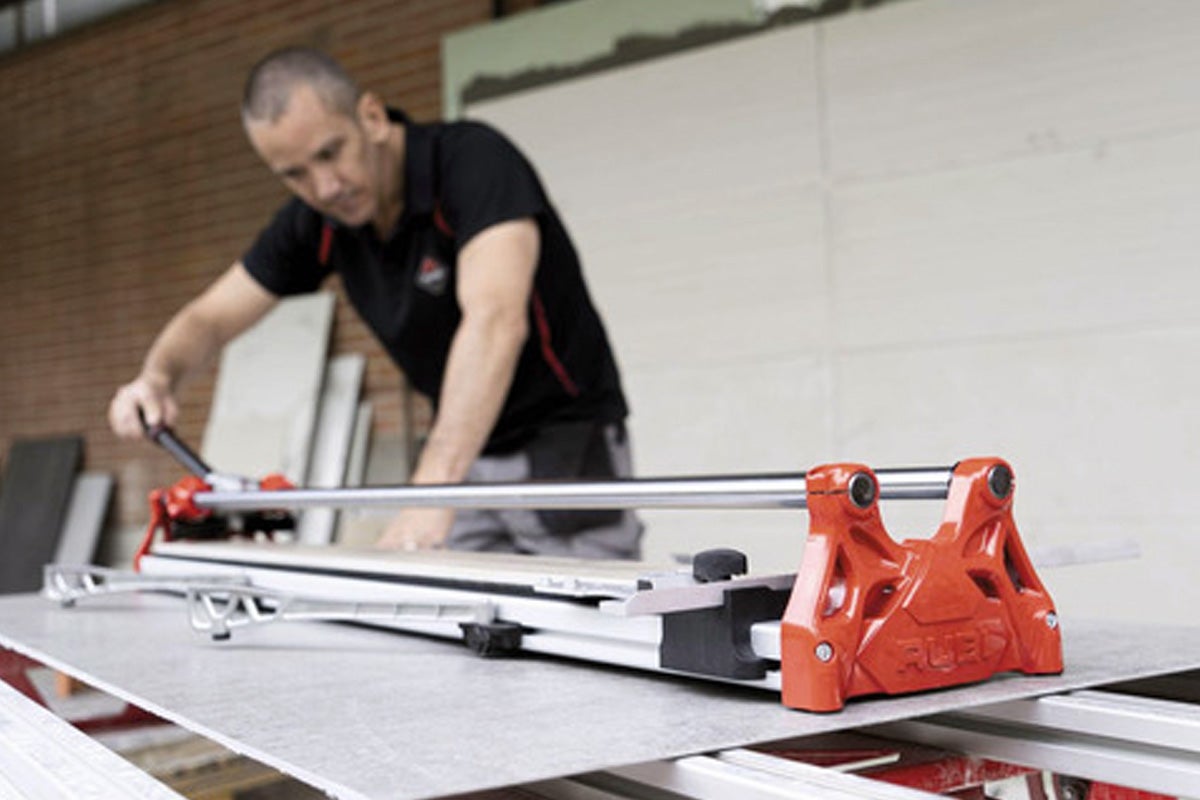 Een man gebruikt een tegelsnijder om tegels op maat te snijden.