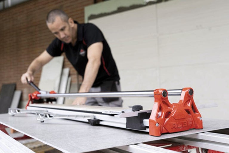 Een man gebruikt een tegelsnijder om tegels op maat te snijden.