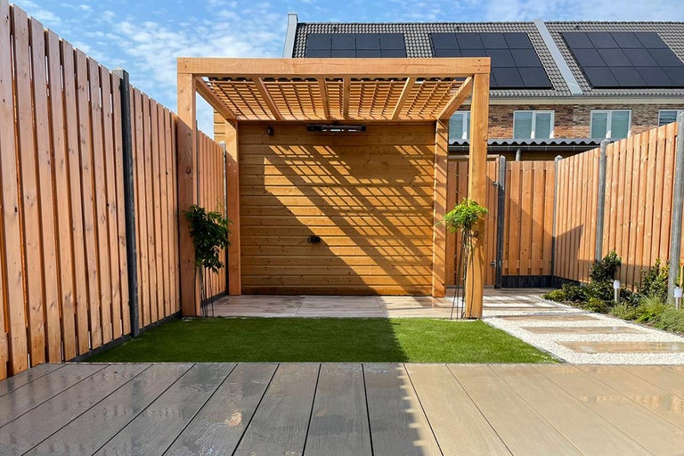 Houten pergola met houten bekleding en houten schutting in een tuin