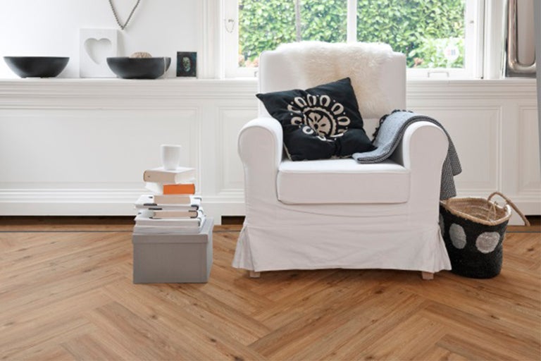 Woonkamer scène met parketvloer, fauteuil en decoratieve elementen voor een gezellige sfeer.