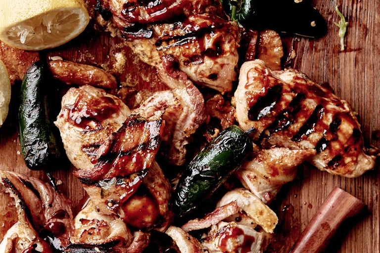 Close-up van gegrilde kip met jalapeños en citroen op een houten plank