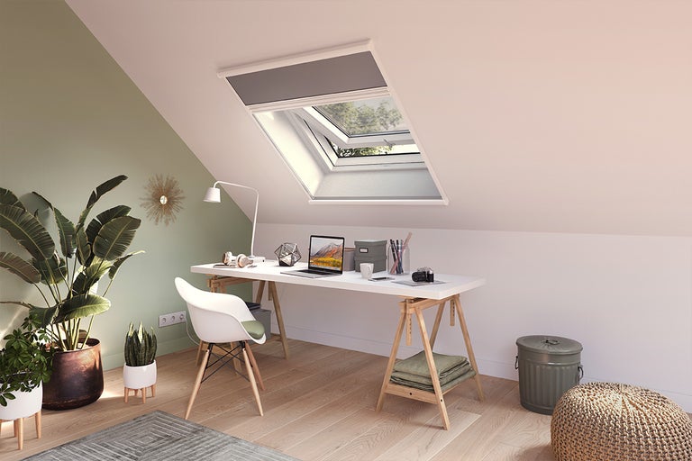Lichte zolderkamer met dakraam en werkplek met bureau