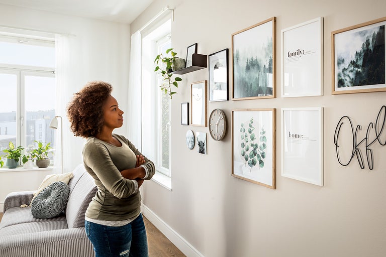 Vrouw bekijkt fotolijsten en wanddecoratie in de woonkamer