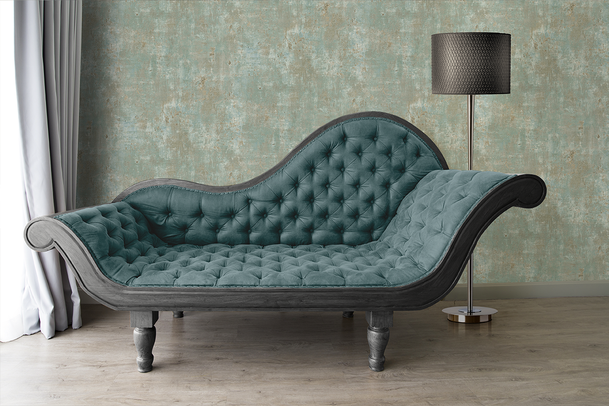 Vliesbehang met betonlook in een woonkamer met klassieke chaise longue, vloerlamp en gordijn op een houten vloer.