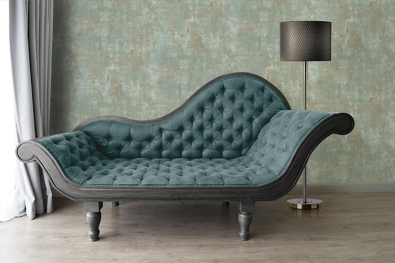 Vliesbehang met betonlook in een woonkamer met klassieke chaise longue, vloerlamp en gordijn op een houten vloer.