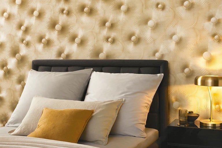 Close-up van een slaapkamer met gestoffeerd hoofdeinde, kussens en gestructureerd behang