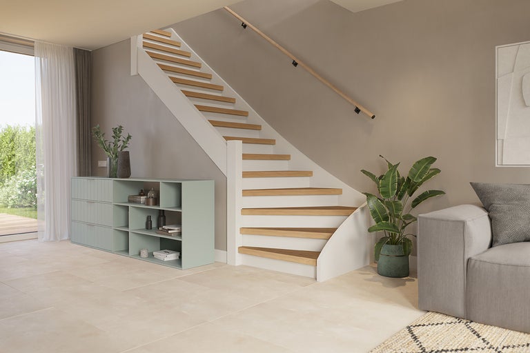 Lichte ruimte met trap, ladekast en bank.
