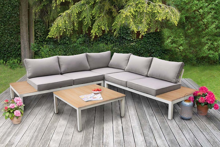 Tuinscene met loungehoek, salontafel, lantaarn en bloemen op een houten terras