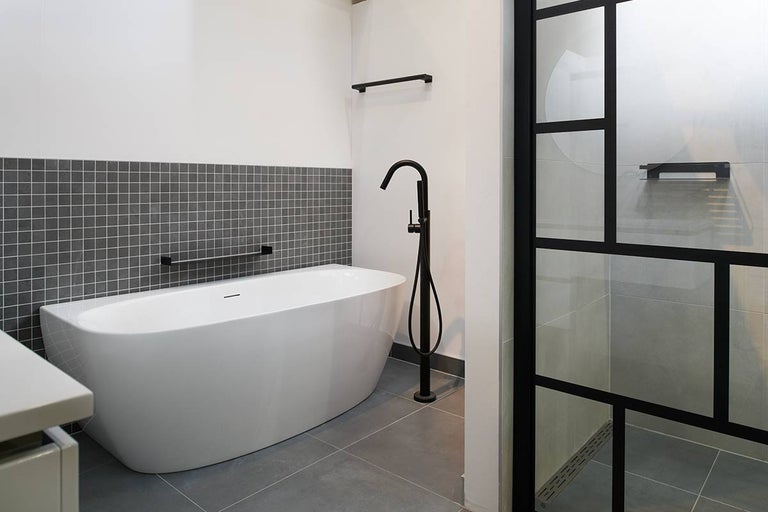 Moderne badkamer met vrijstaand bad, douchecabine met zwart frame en grijze tegels
