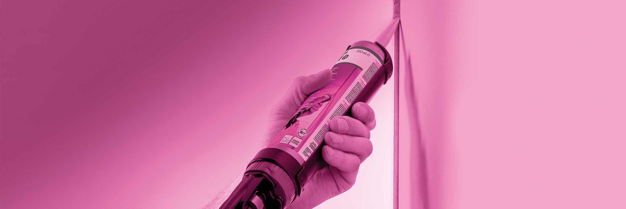 Een hand houdt een patroon met afdichtmiddel vast en brengt het aan op een voeg.