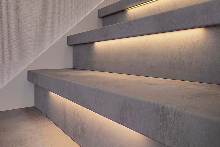 Moderne trap in betonlook met warme led-verlichting onder de treden.