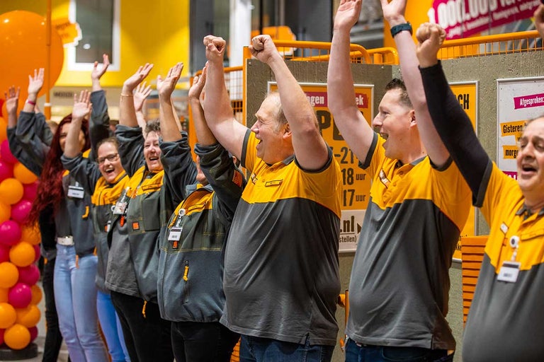 Een groep Hornbach medewerkers viert feest met opgeheven armen.