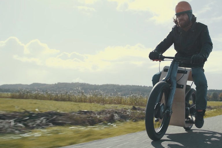 Een man rijdt op een elektrische motorfiets op een landweg.