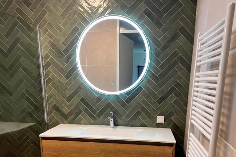 Badkamer met wastafel, spiegel met verlichting en radiator