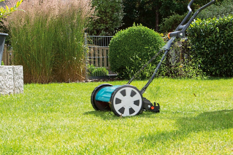 Handmatige gazonmaaier op een gazon in de tuin.