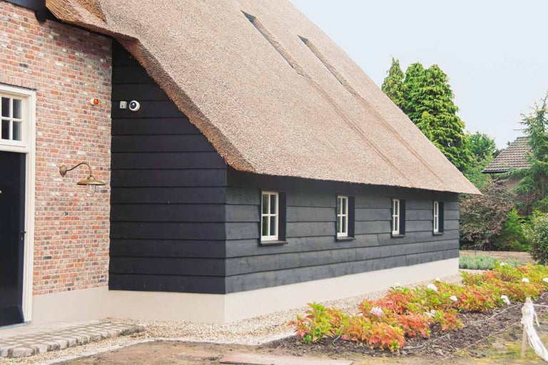 Boerderij met rieten dak, houten gevelbekleding en bakstenen elementen.