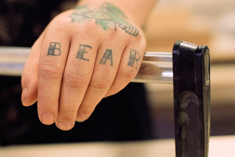 Een hand met tatoeages houdt een handgreep vast.