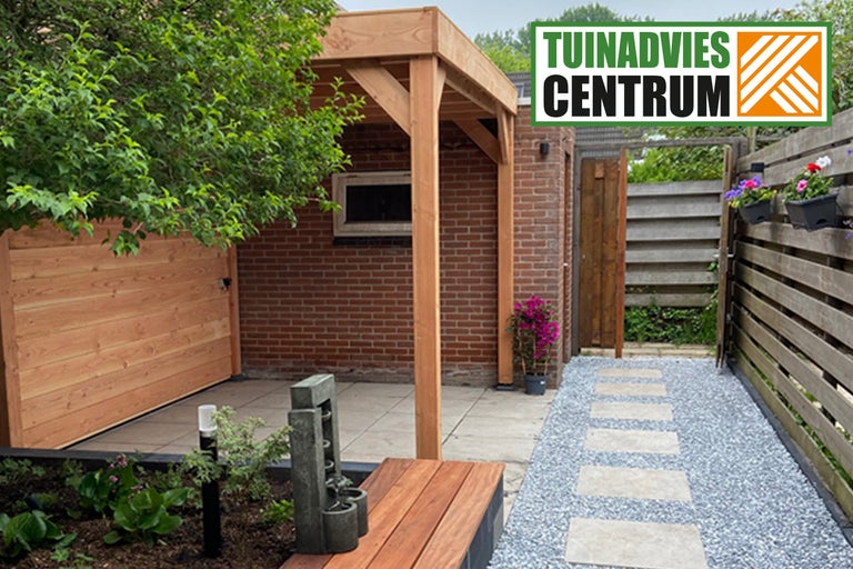 Aangelegde tuin met houten terras, grindpad en schutting