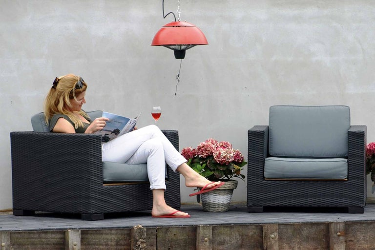 Terras met rotan fauteuils en een vrouw die een tijdschrift leest